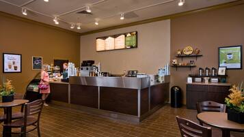A restaurant with a counter, seating area, and menu board.