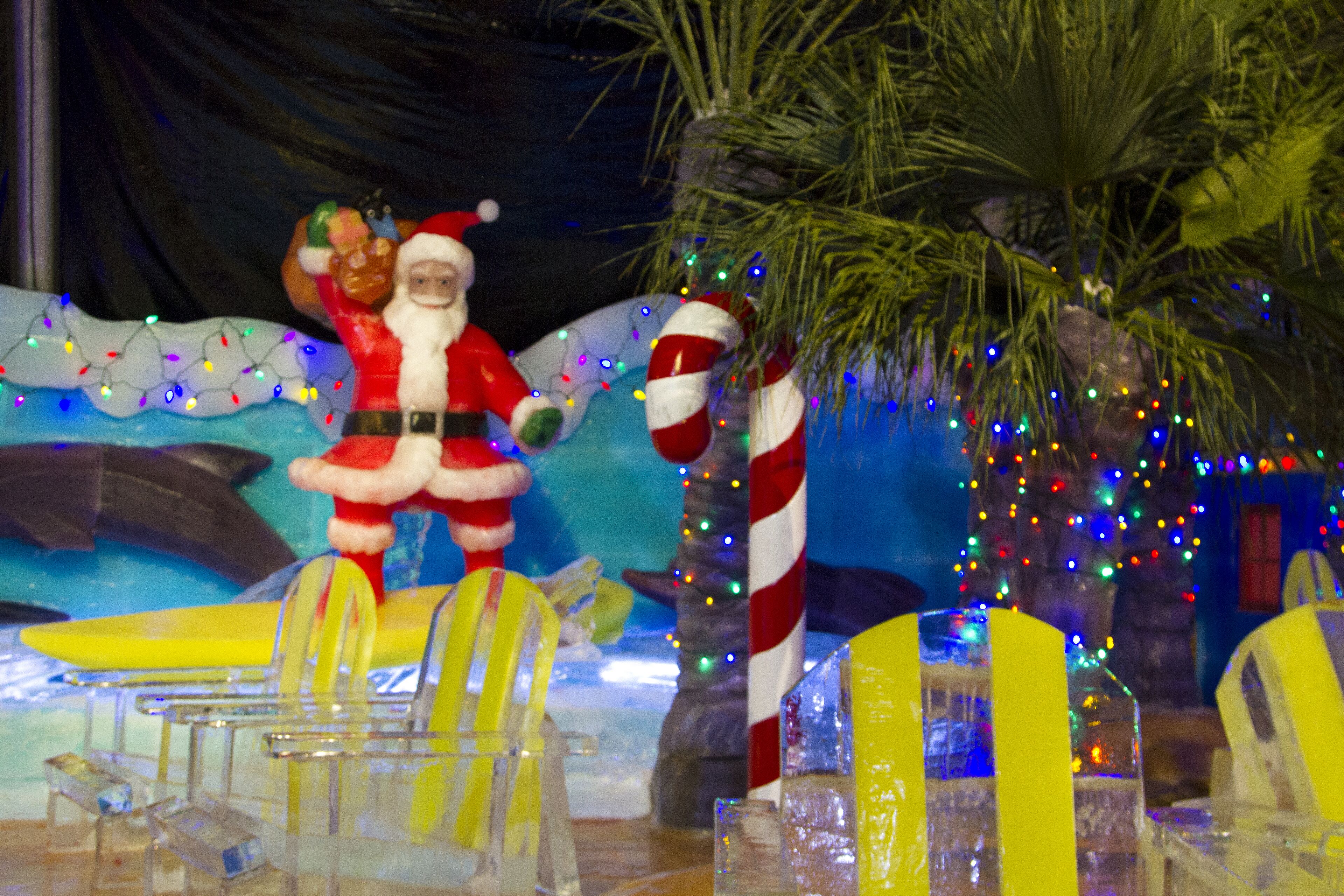A festive scene with a Santa Claus figure, a palm tree, and a surfboard.