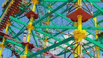 A group of people standing in front of a large, colorful amusement park ride with a tall structure and multiple levels.