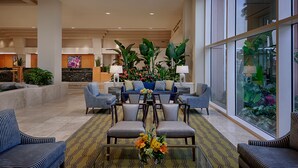 A spacious lobby with a reception desk, seating area, and large windows.