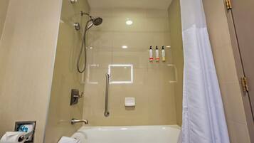 Un baño moderno con ducha de vidrio, una bañera blanca, un perchero para toallas y un secador de manos.