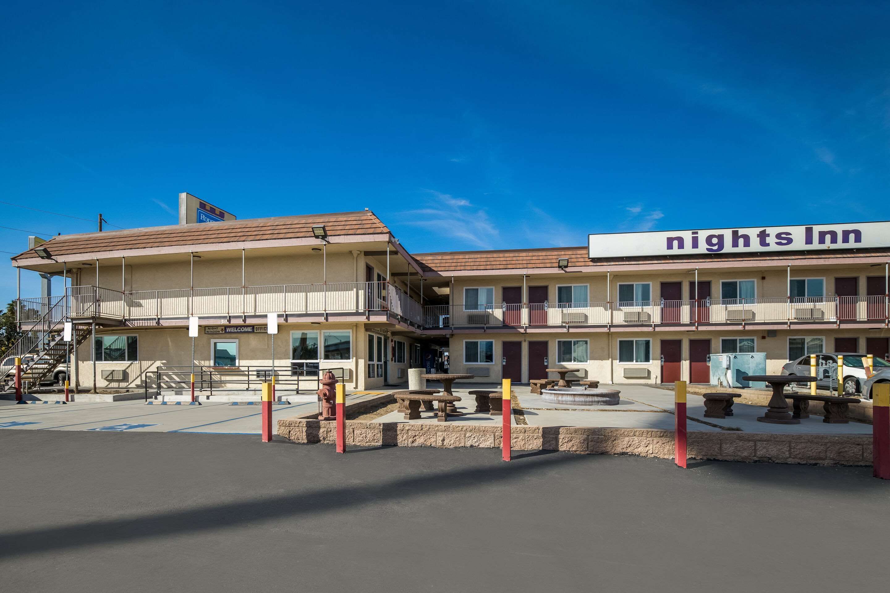 A two-story motel with a 'nights Inn' sign, outdoor seating, and a clear blue sky.