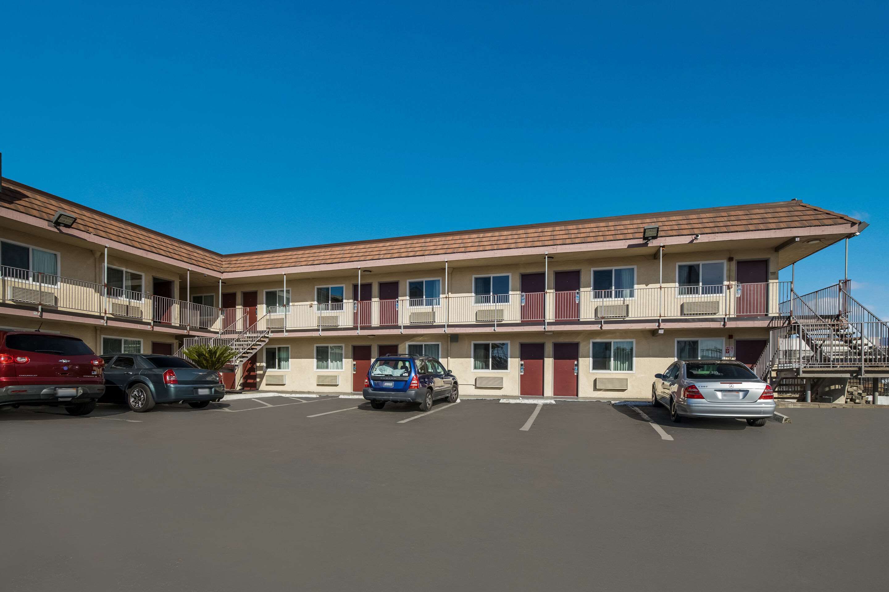A motel with a parking lot, multiple floors, and a fire escape.