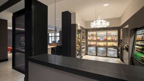 Ein modernes Interieur mit einer Rezeption, einer mit Getränken gefüllten Minibar und einem Kronleuchter.