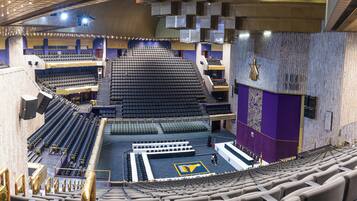 Un vaste auditorium intérieur doté de gradins, d’une scène et d’un grand symbole en forme d’étoile sur le mur.