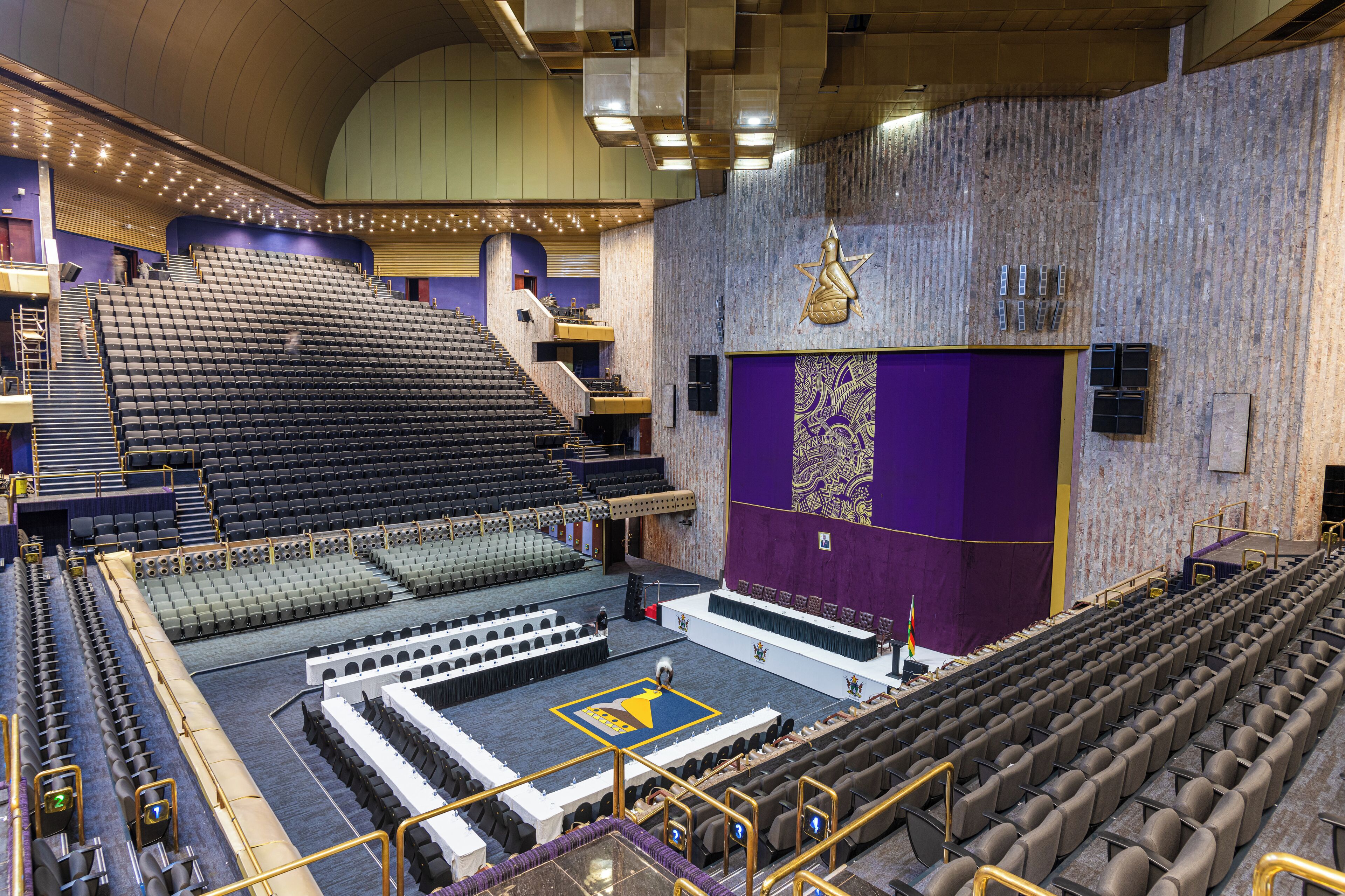 A theater with multiple levels of seating, a stage, and a decorative wall with a star emblem.