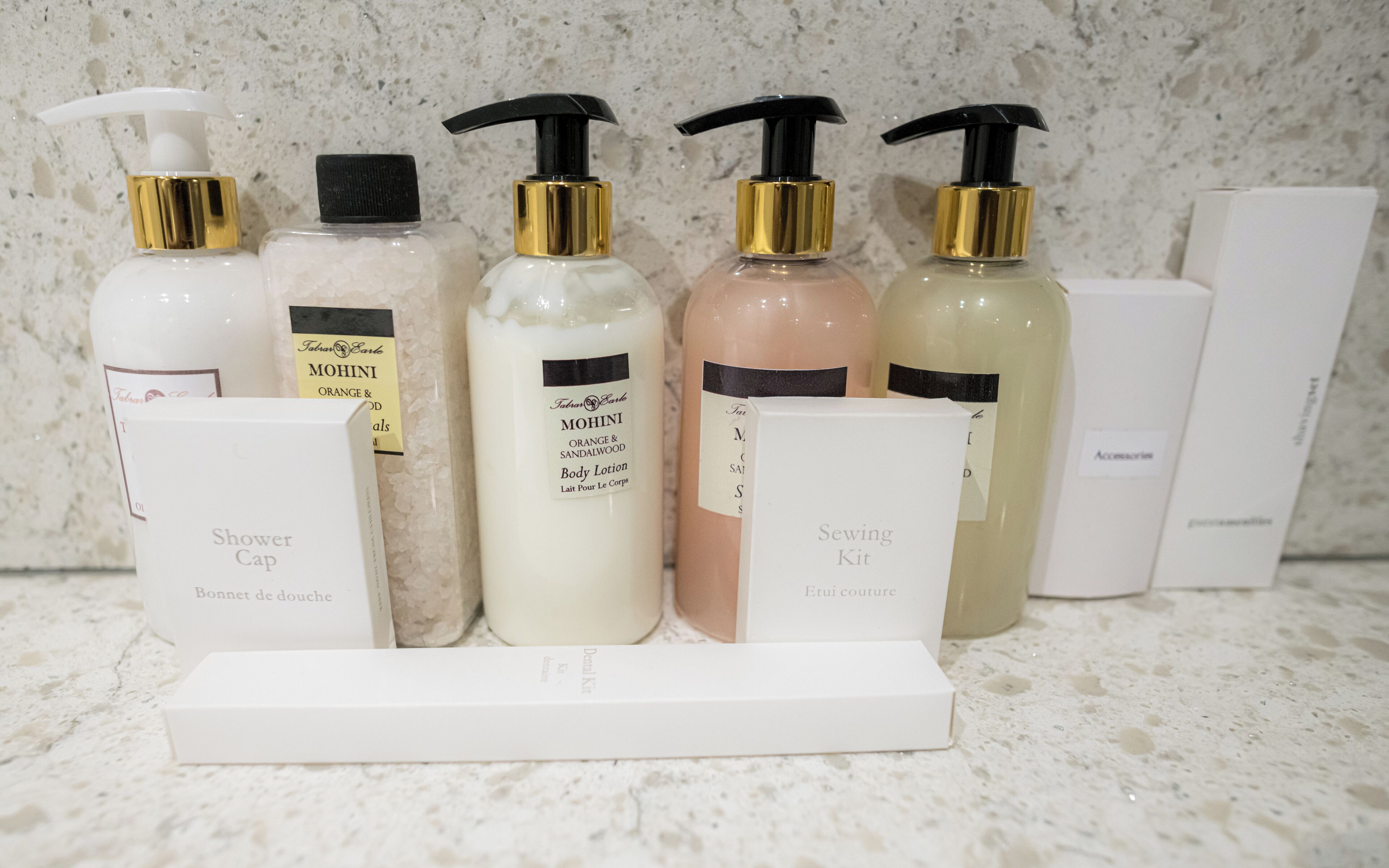 A display of various toiletries including a shower cap and a sewing kit, arranged on a countertop.