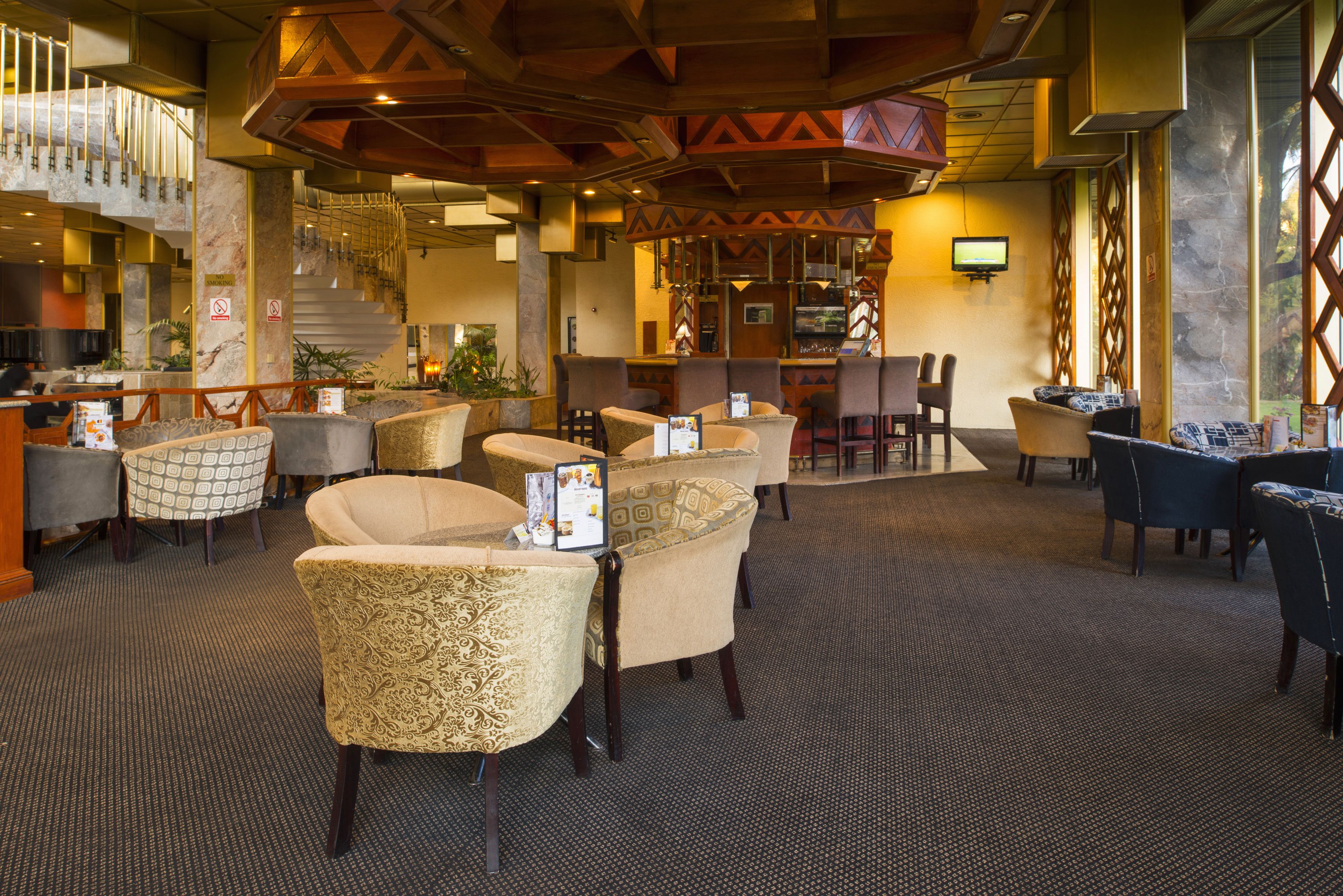 A lobby with a bar area, seating arrangements, and a staircase.