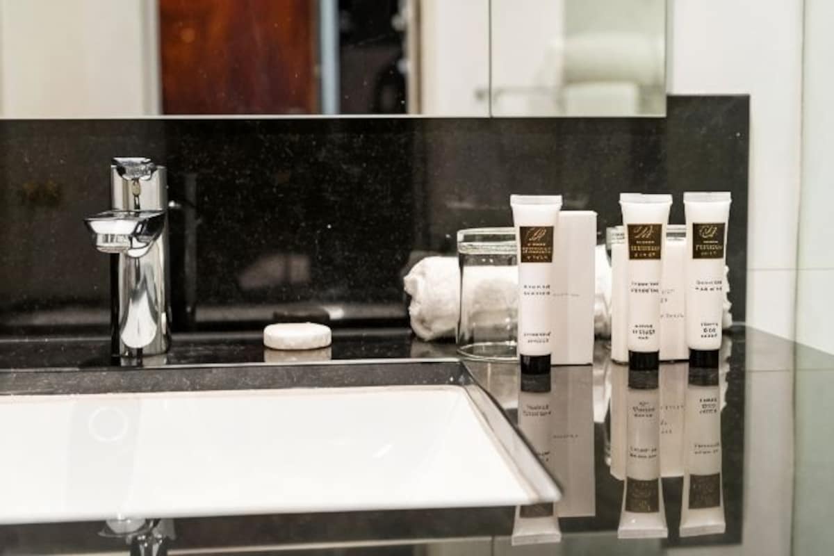 A bathroom with a black countertop, a white sink, and several toiletries including a soap bar, a toothbrush, and a tube of toothpaste.