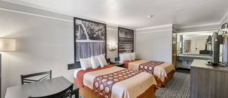 Una habitación de hotel con dos camas, un escritorio, una silla y un televisor.