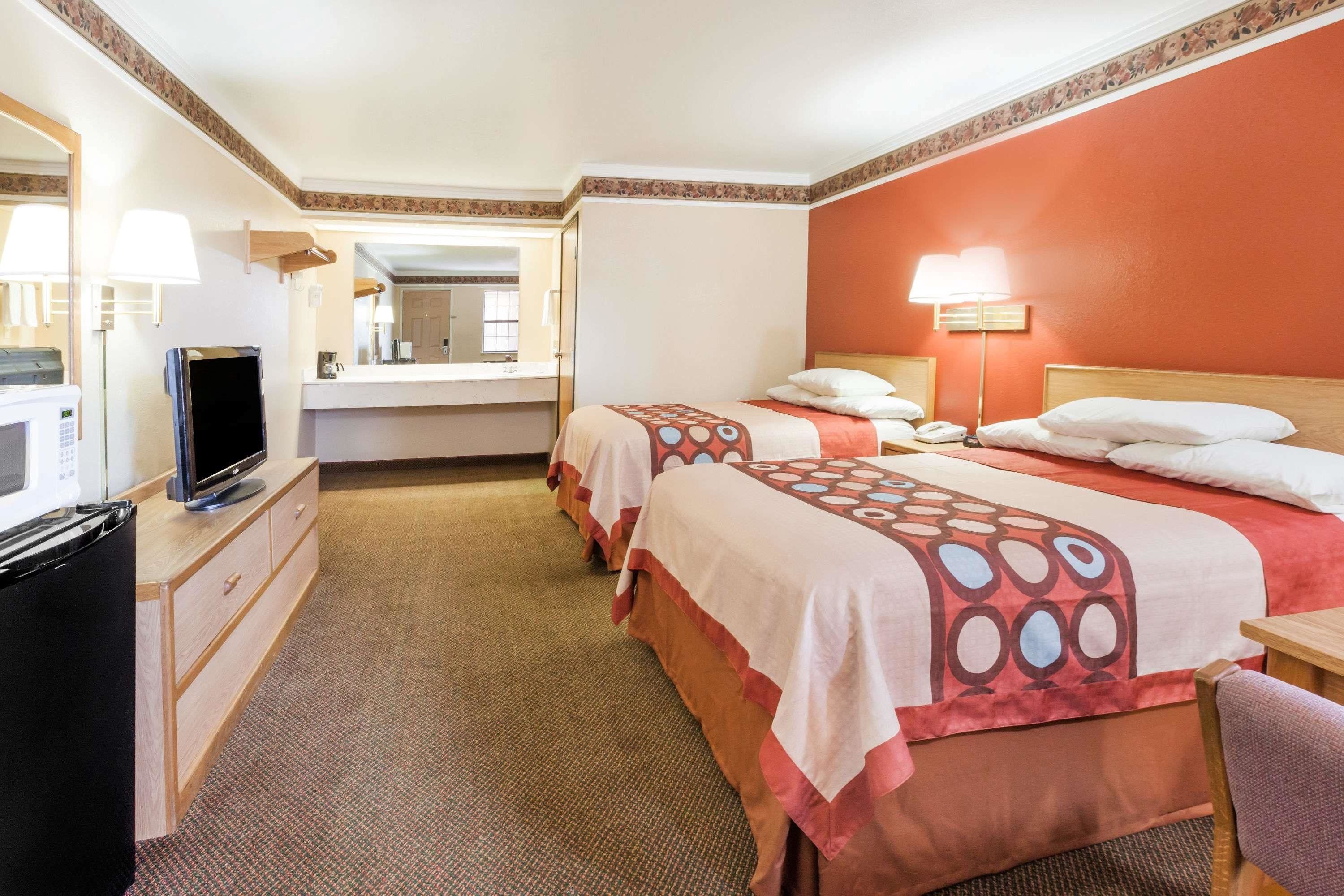 A hotel room with two beds, a television, a desk, and a mirror.