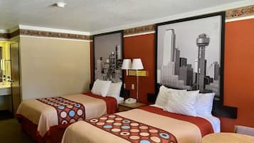 A hotel room with two beds, a cityscape mural, a lamp, and a small table.