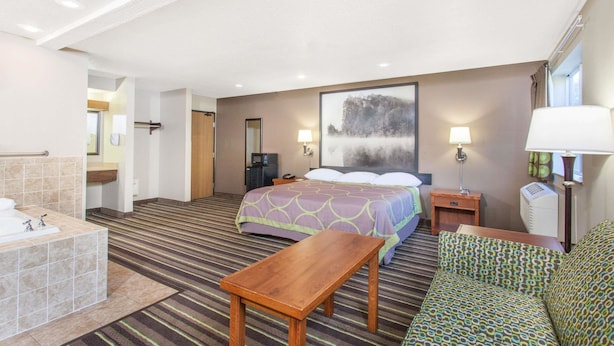 Une chambre d’hôtel comprenant un lit, un bureau, une chaise, une salle de bain avec baignoire et une grande fenêtre.