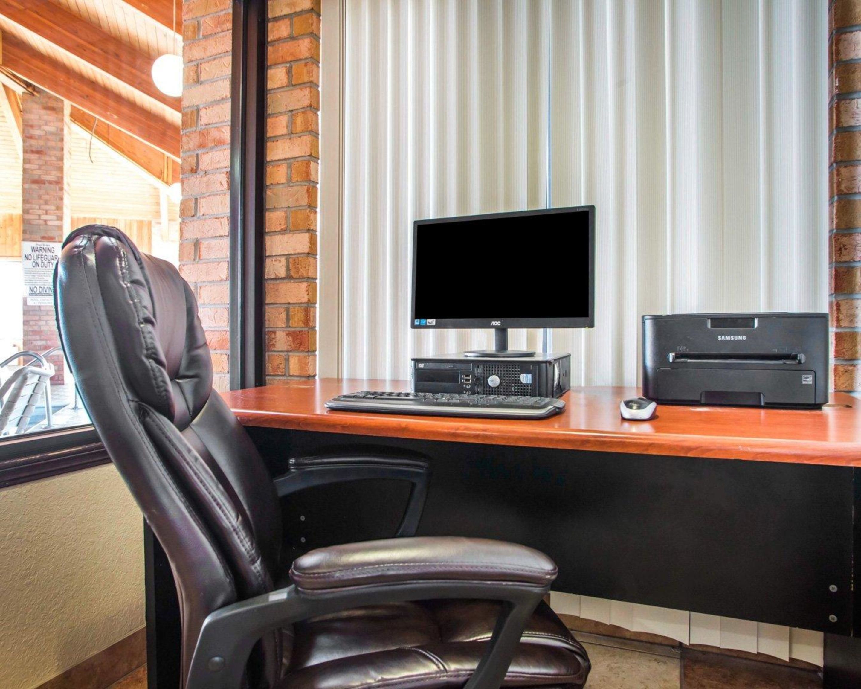 A workspace with a leather chair, a desk, a computer monitor, a keyboard, a mouse, and a printer.