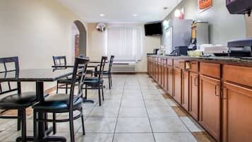 A dining area with a long counter, multiple chairs, and a television mounted on the wall.