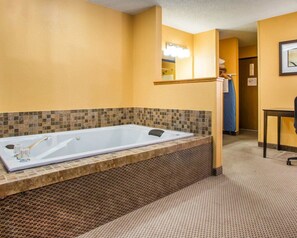 A bathroom with a large bathtub, a shower area, and a sink.