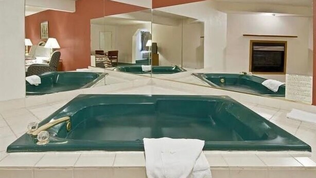 A large, rectangular hot tub in a room with a tiled floor and a mirror reflecting the room. - Travel Inn & Suite (Springerville)