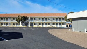 A motel with a red-tiled roof, multiple balconies, and a parking lot. - Travel Inn & Suite (Springerville)