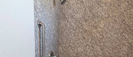 Ein Badezimmer mit Dusche, Toilette und einer Tür mit Griff.