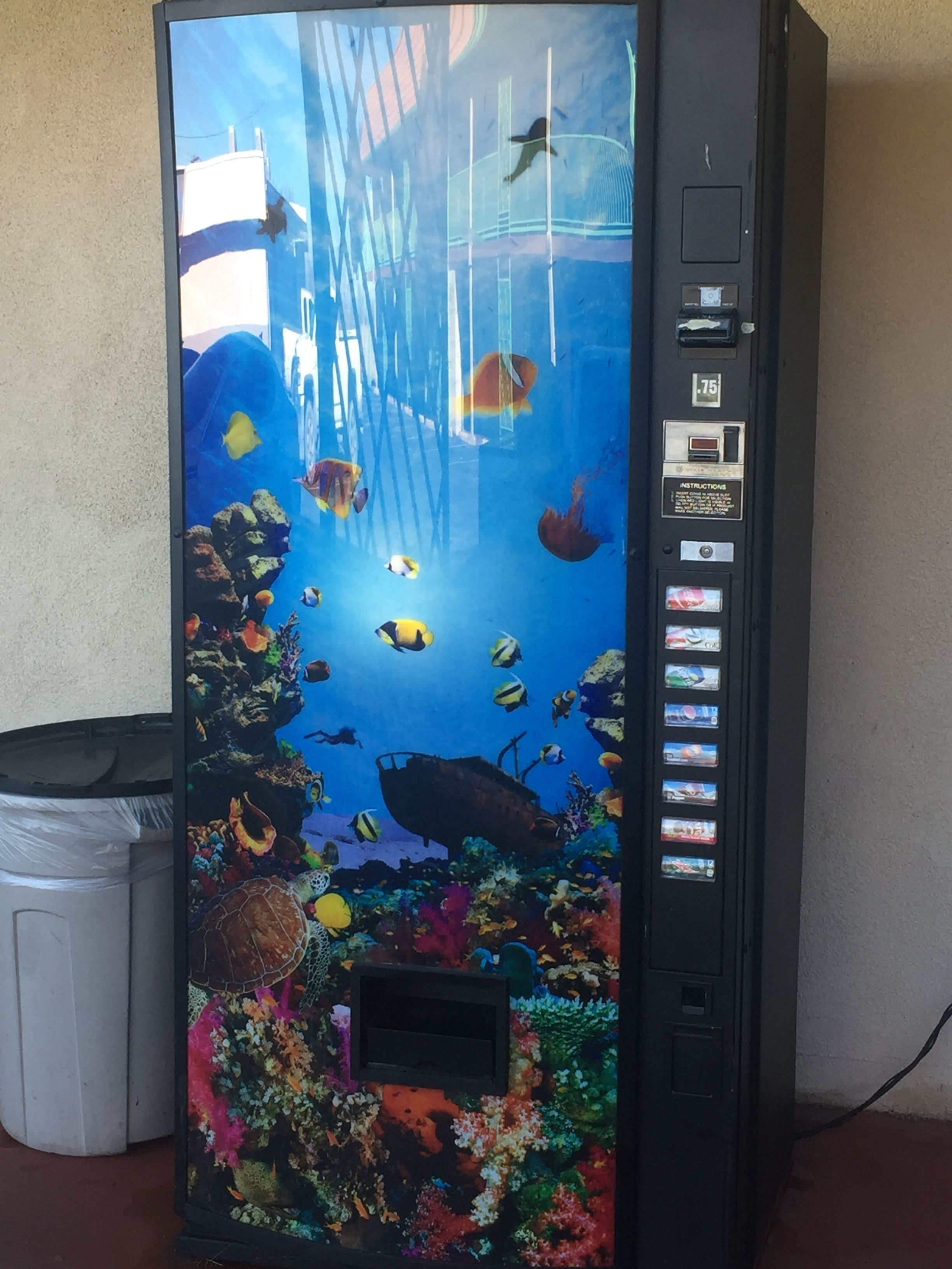 Máquina expendedora con acuario que muestra diversos peces y corales.