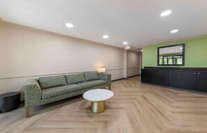 A room with a green sofa, a round table, a black cabinet, and a mirror on the wall. - Extended Stay America Suites Ft Lauderdale Cyp Crk NW 6th Wy (Fort Lauderdale)