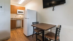 Una cocina compacta con microondas, refrigerador y una mesa de comedor con sillas.