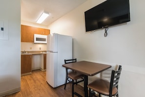 Una cocina compacta con microondas, refrigerador y una mesa de comedor con sillas.