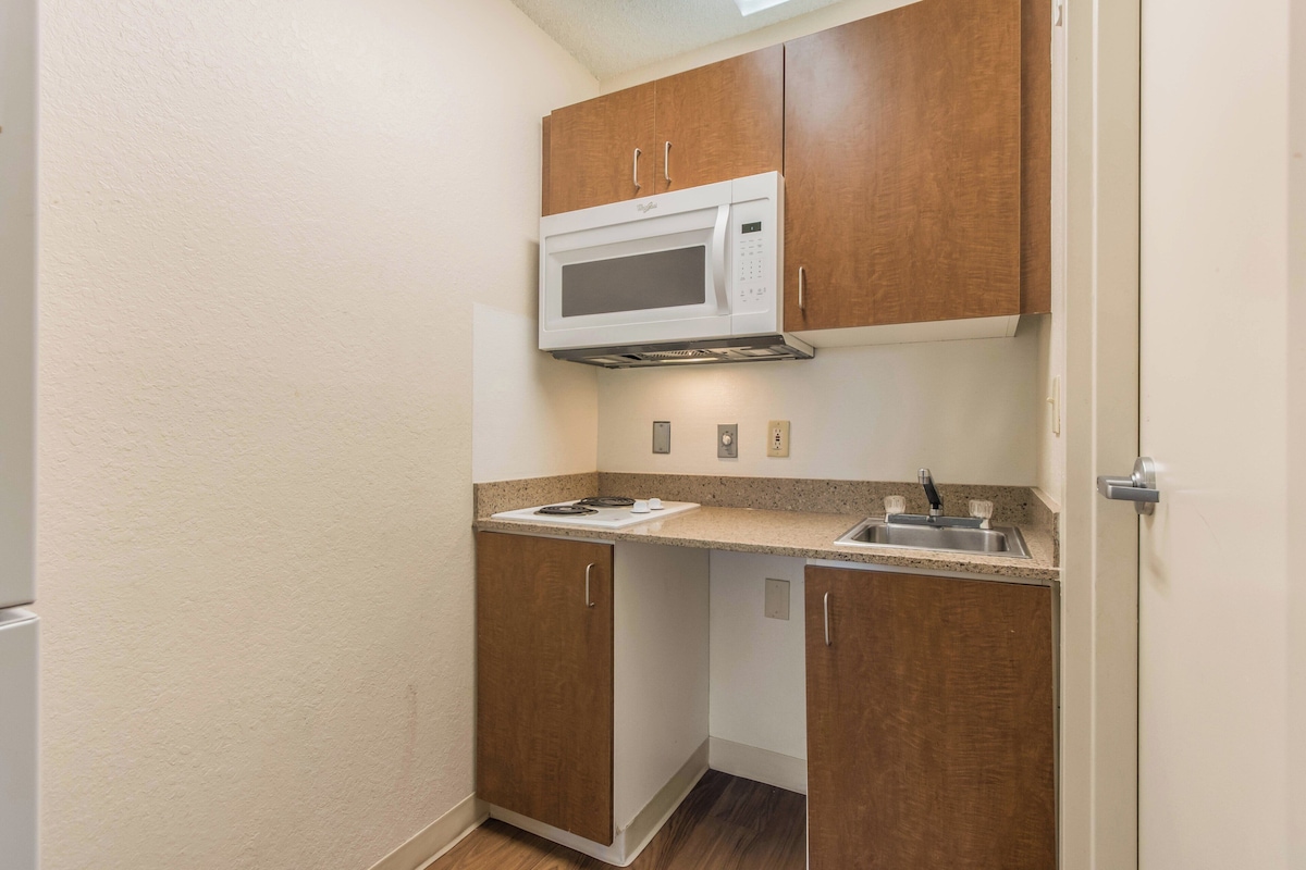 Cocina pequeña con microondas, pileta y armarios de madera.