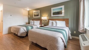 Habitación de hotel con dos camas, una mesita de noche con lámpara, un calentador en la pared y una puerta que da a otra habitación.