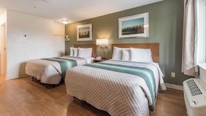 Habitación de hotel con dos camas, una mesita de noche con lámpara, un calentador en la pared y una puerta que da a otra habitación.