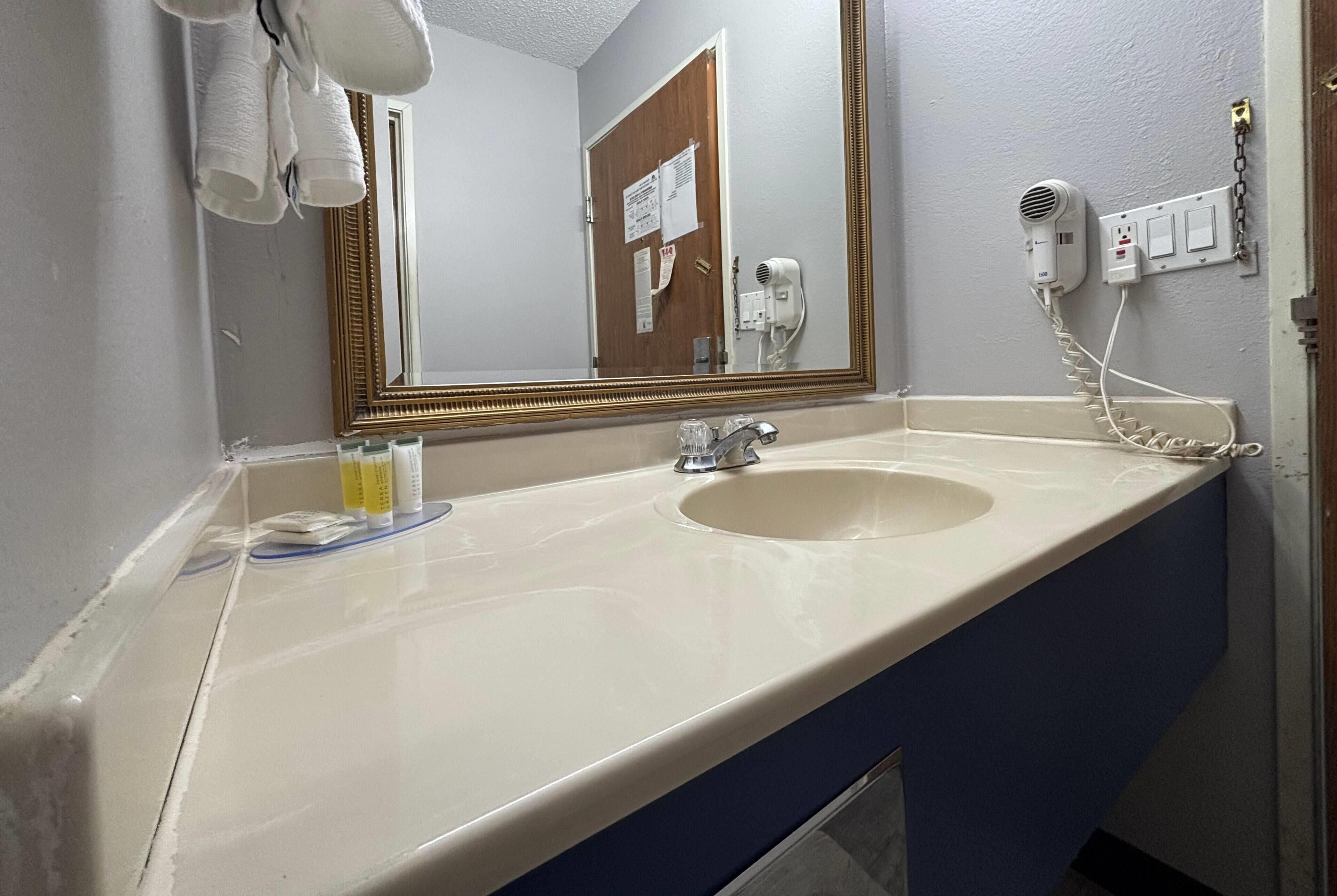 Un bagno con lavandino, specchio e asciugacapelli.