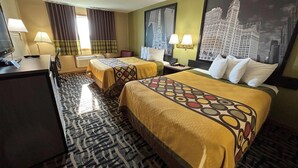 Habitación de hotel con dos camas, un escritorio, un televisor y una alfombra estampada.