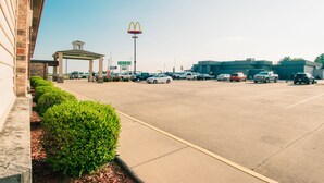 Un estacionamiento con el letrero de McDonald's, una zona techada y un edificio de fachada de ladrillo.