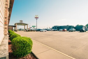 Un estacionamiento con el letrero de McDonald's, una zona techada y un edificio de fachada de ladrillo.