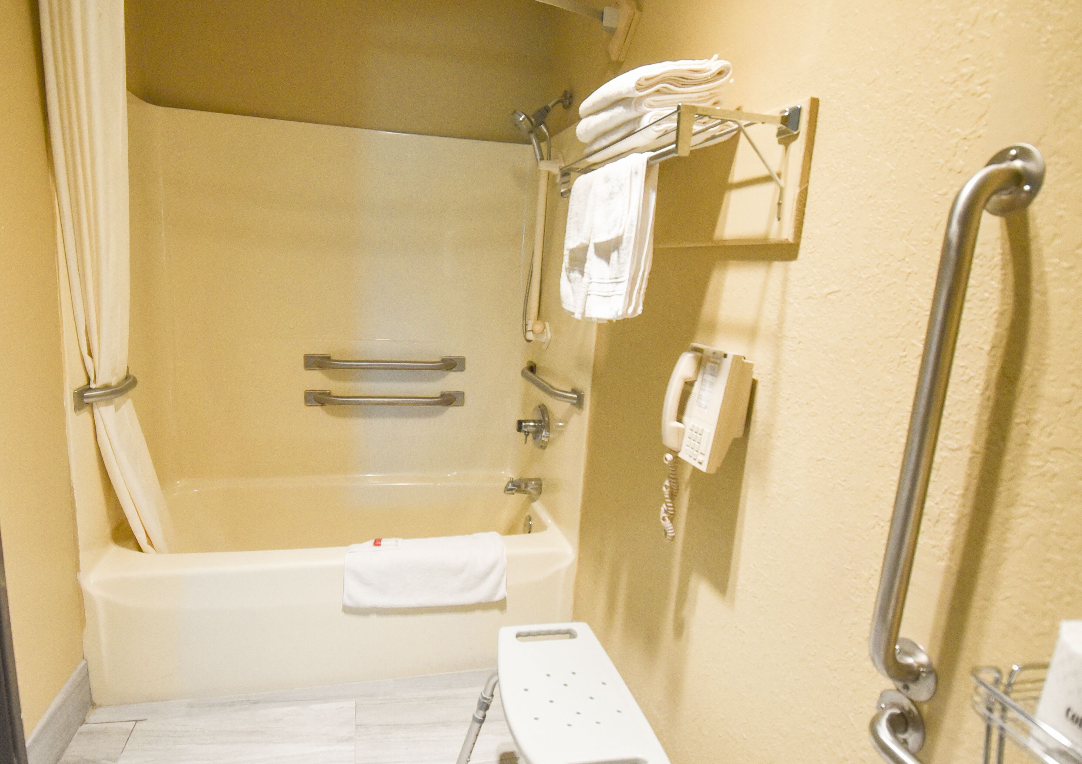 A bathroom with a bathtub, a shower, a toilet, and a grab bar.