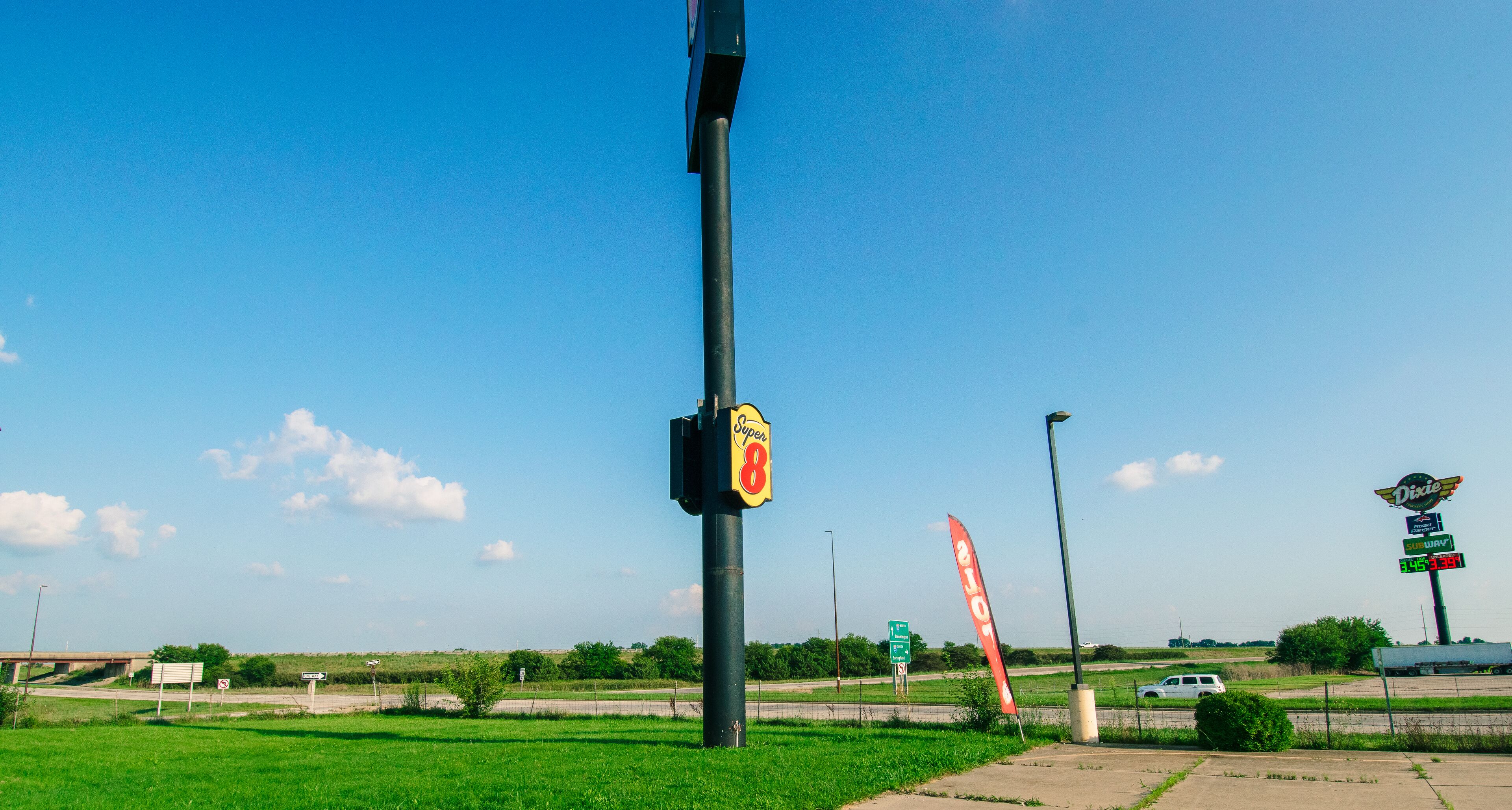 A roadside sign with a Super 8 logo, a Dixie diner sign, and a gas price sign.
