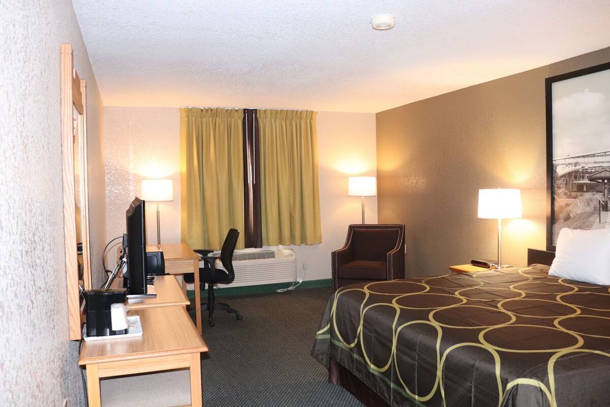 A hotel room with a bed, desk, chair, and two lamps.