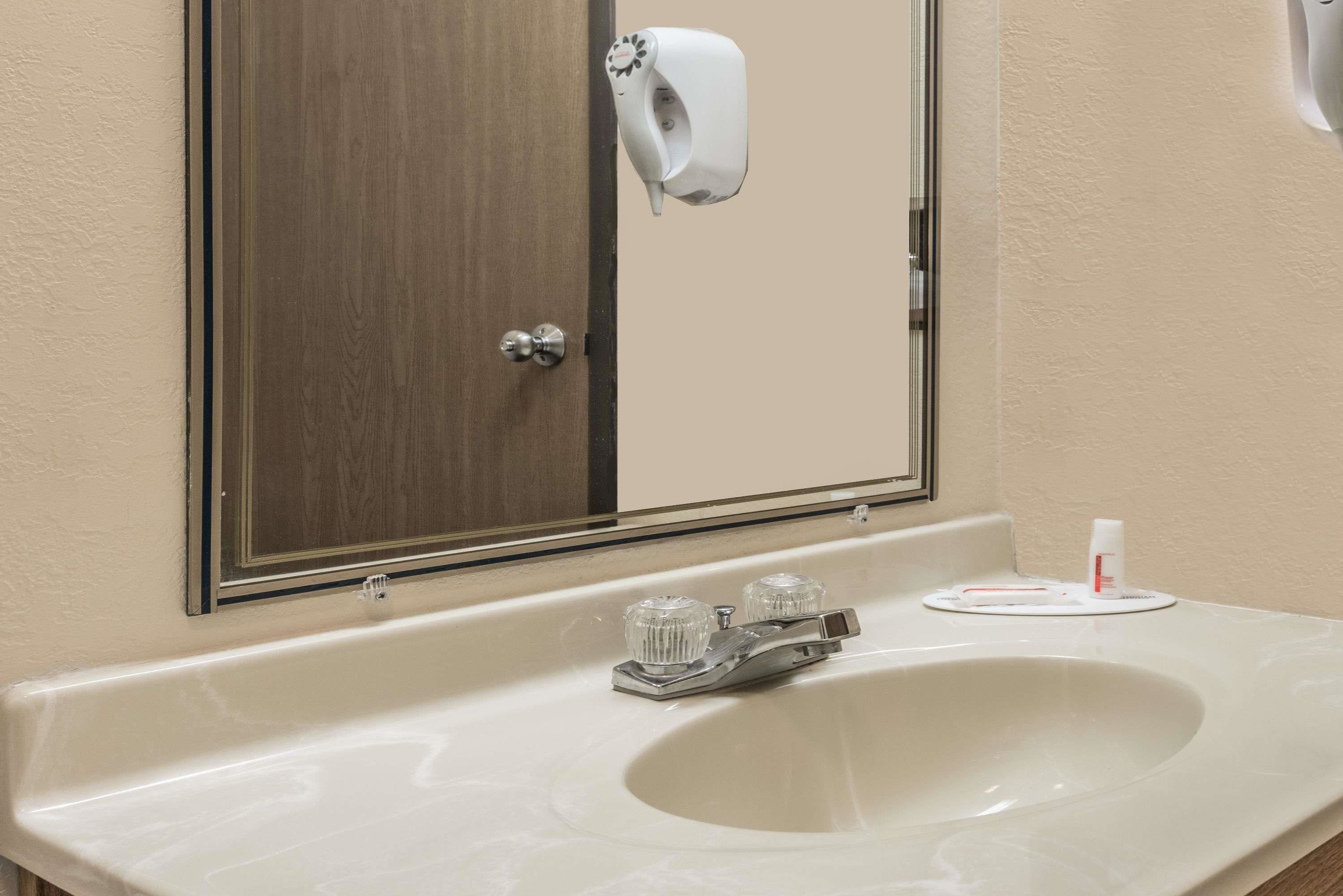 Un baño con lavamanos blanco, un espejo y dispensador de toallas de papel.