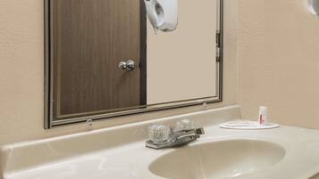 Un baño con lavamanos blanco, un espejo y dispensador de toallas de papel.