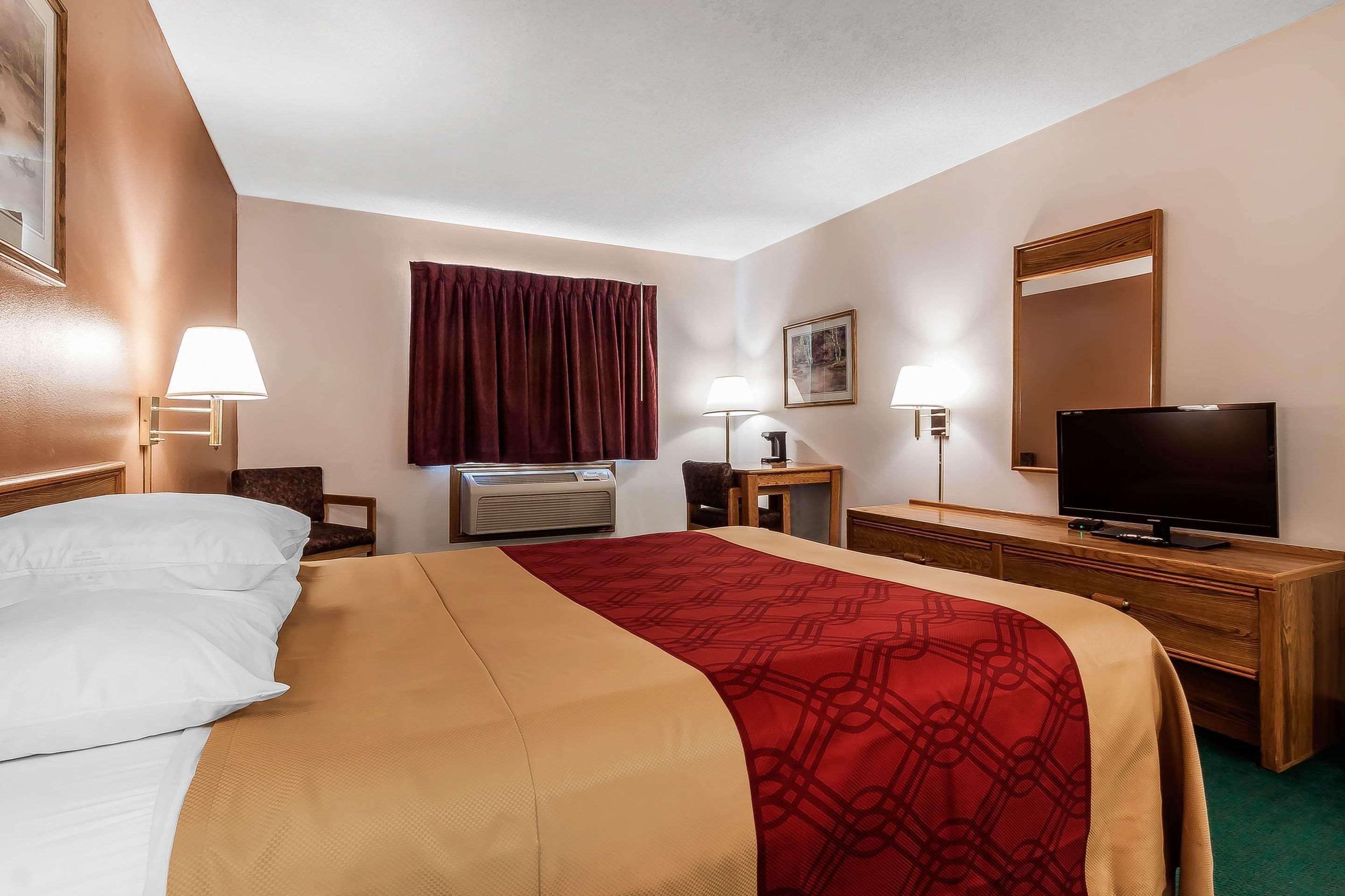 A hotel room with a bed, a TV, a desk, and a chair.