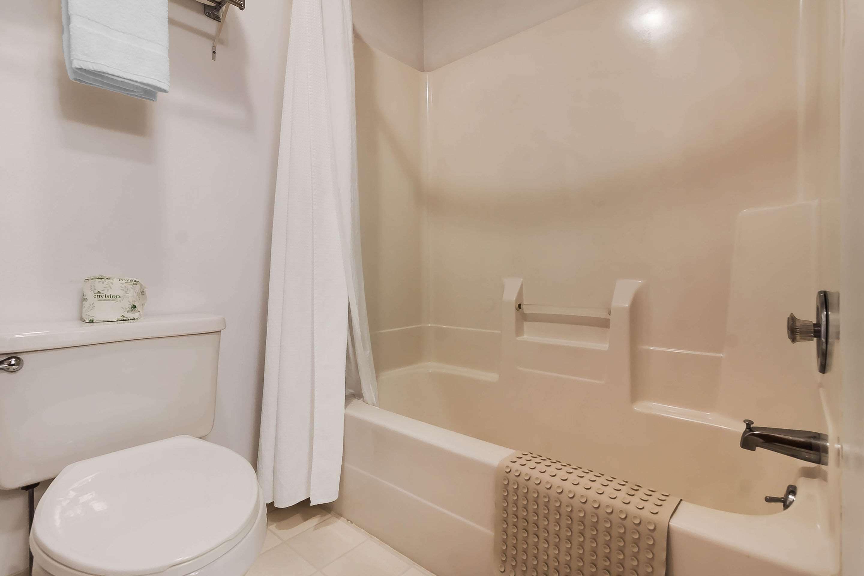 A bathroom with a toilet, a bathtub, and a shower area.