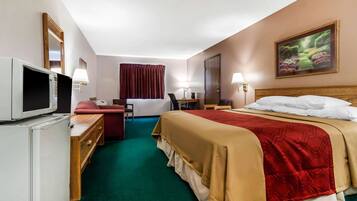 A hotel room with a bed, a desk, a chair, a television, and a painting on the wall.