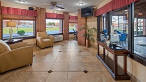 A lobby with a seating area, a coffee station, and large windows with a view of the parking lot.