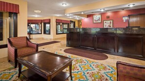 A lobby with a reception desk, seating area, and patterned carpet.