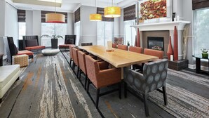 A spacious dining area with a long wooden table, multiple chairs, and hanging pendant lights. - Hilton Garden Inn Albuquerque North/Rio Rancho (Rio Rancho)