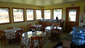 A dining area with round tables and chairs, a kitchen counter, and a water dispenser. - Lakeview Inn Centralia (Centralia)