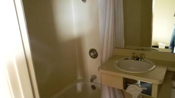 A bathroom with a bathtub, a sink, and a mirror.
