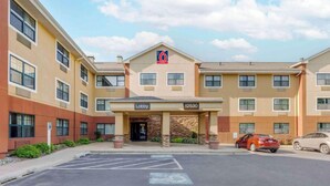 A hotel with a '6 suites' sign, a lobby entrance, and a parking lot with two cars.