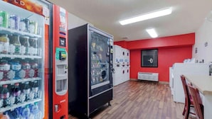 A room with vending machines, a white refrigerator, and a red wall.