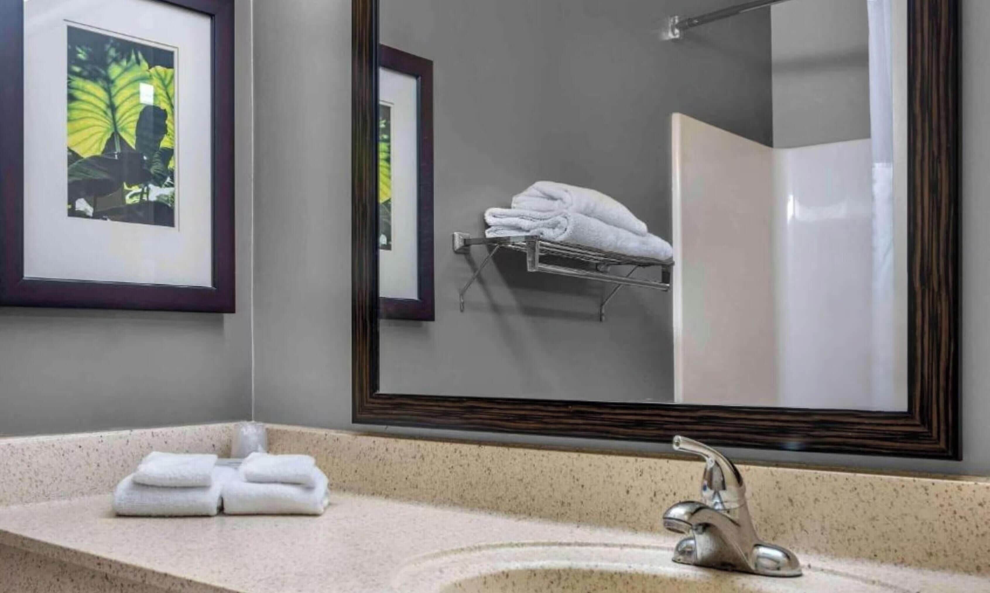 A bathroom with a sink, mirror, and towel rack.
